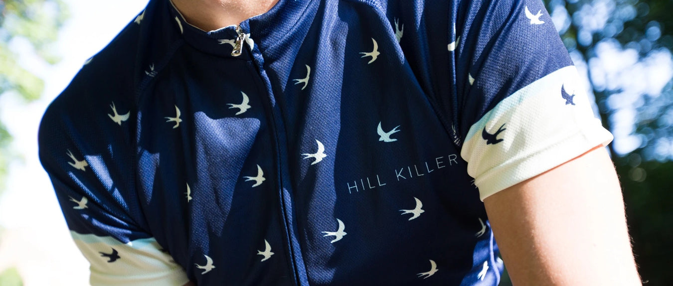 A closeup of a Hill Killer short sleeve men's jersey in navy blue with a small white bird pattern and white cuffs.